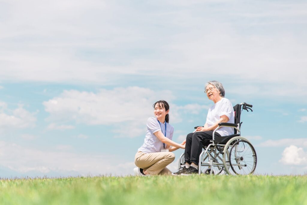 車椅子になる高齢女性と介護士