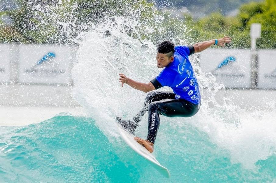 ダイナミックな波しぶきを立てながらアダプティブサーフィンを楽しむ男性当事者