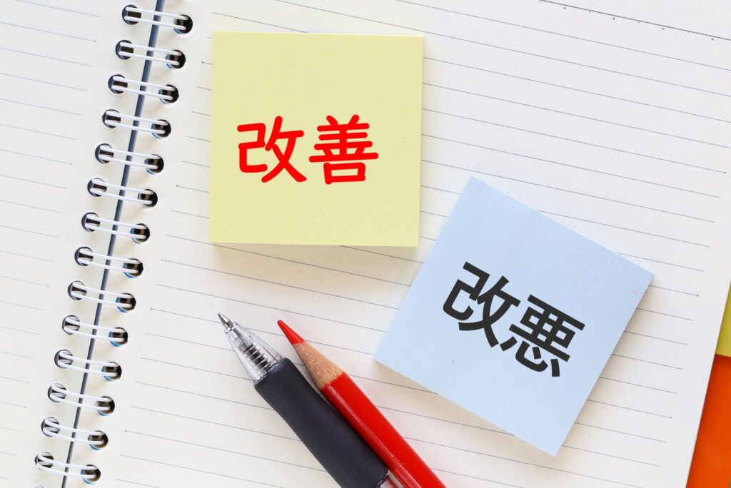 ノートに貼られた2枚の付箋。片方には「改善」、もう片方には「改悪」の文字