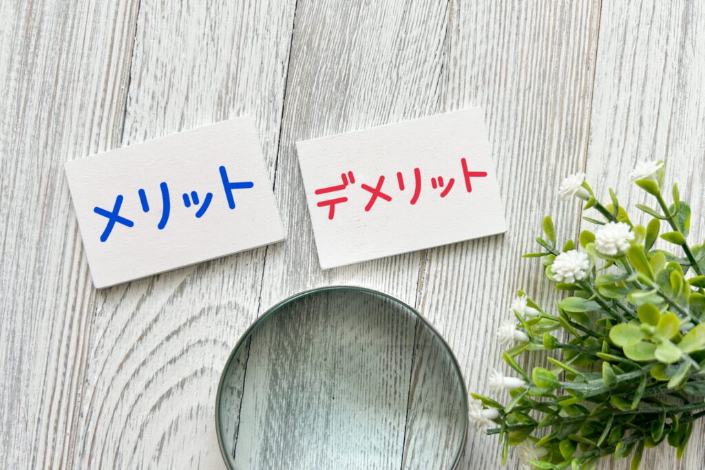 木目調の床の上に「メリット」と「デメリット」のプレート