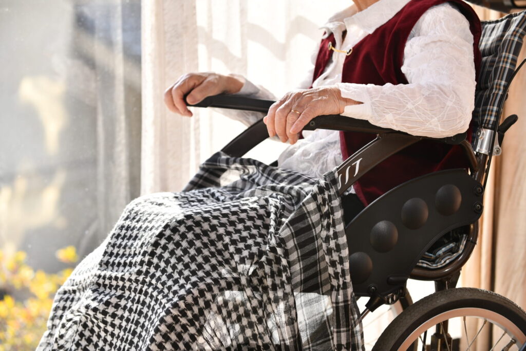 ひざ掛けをまとって車椅子に座る高齢者